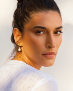 Retrato de mulher com brinco de pérola e maquiagem suave.