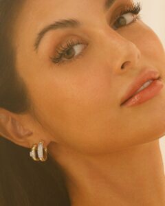 Close-up de mulher com brincos dourados e pele radiante